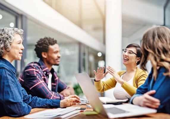 coach watching team dynamics while speaking to three people at a table