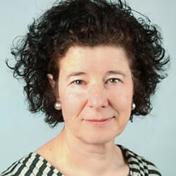 Lesley Trenner PCC headshot photo, smiling woman with dark curly hair wearing striped shirt in front of light background