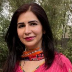 Khadija Usman Headshot photo, dark haired woman smiling looking at camera outside