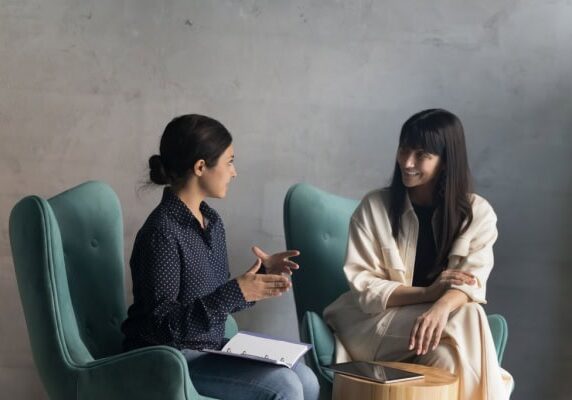coach and client sitting in green armchairs and coach speaking while client listens