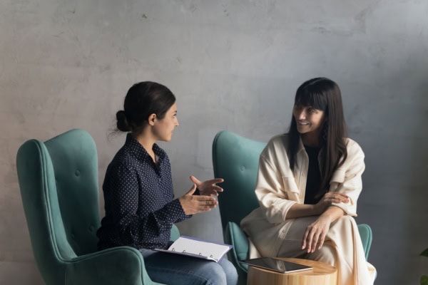 coach and client sitting in green armchairs and coach speaking while client listens